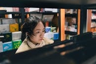 Asian Woman Browsing Bookshelves in Store