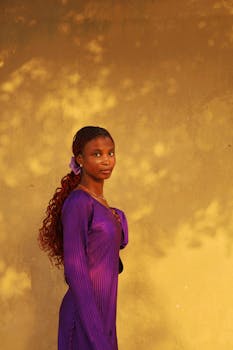 Portrait of a woman in a purple dress against a warm golden backdrop, captured at sunset.