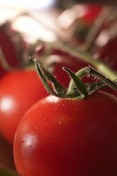Vibrant close-up of fresh red tomatoes on a vine with detailed texture, perfect for food themes.