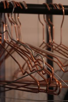 A collection of copper wire coat hangers hanging on a rod in Berlin.