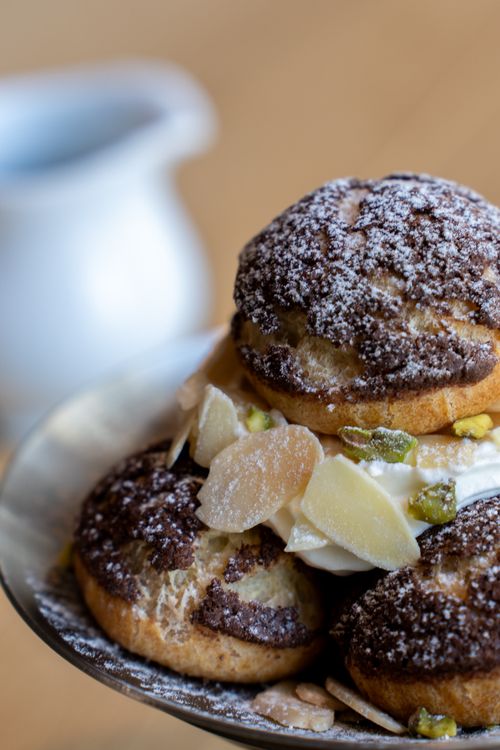 Free Delicious chocolate cream puffs garnished with almonds and whipped cream, perfect for dessert lovers. Stock Photo