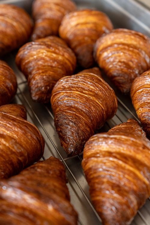Free Golden brown croissants cool on a rack in a Tokyo bakery, perfect for breakfast lovers. Stock Photo