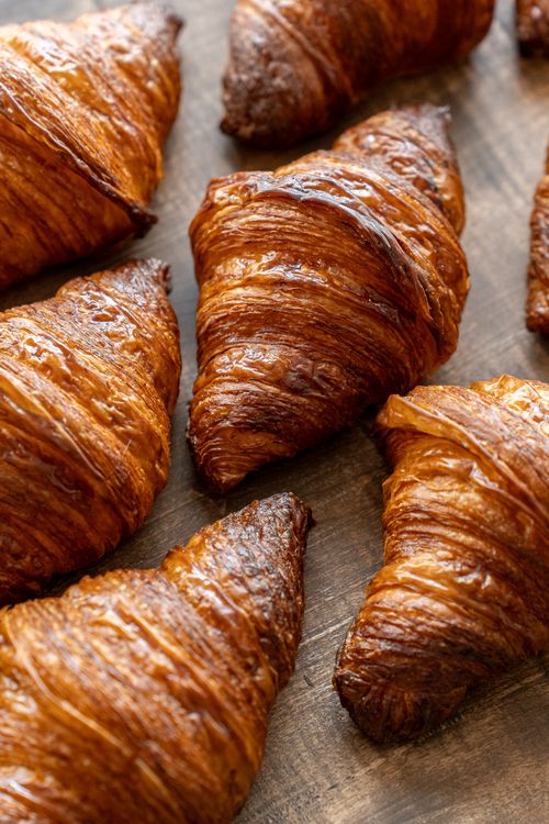 Free Freshly baked golden croissants displayed on a rustic wooden surface, capturing an artisanal bakery atmosphere in Tokyo. Stock Photo