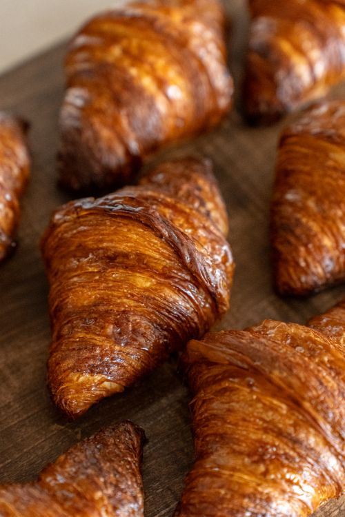 Free Golden, flaky croissants displayed on a wooden surface at a Tokyo bakery. Stock Photo