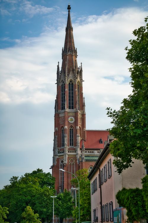 Free Stunning view of a Gothic Revival style church tower surrounded by lush greenery in Munich, Germany. Stock Photo