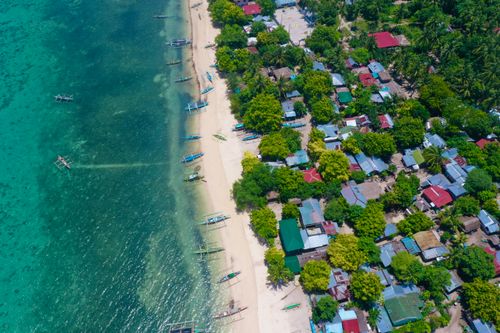 Free Stunning aerial capture of a tropical coastal village with boats and lush greenery. Stock Photo