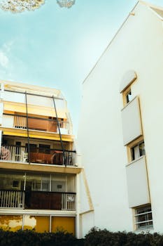 Contemporary multi-story apartment with large windows and balconies under a clear blue sky.