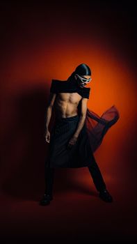 Stylish man with a bold fashion statement in a dramatic red studio setting, radiating confidence.