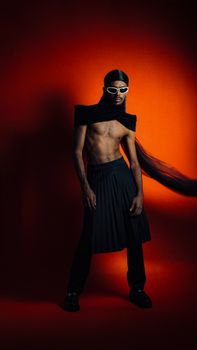 Bold male fashion featuring a model in avant-garde attire against a vibrant red backdrop.