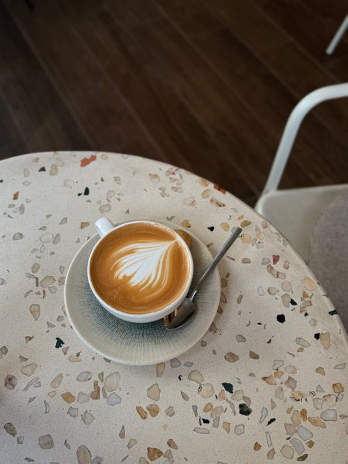 Free Latte with art on a terrazzo table top, cozy cafe setting. Stock Photo