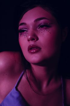 Close-up portrait of a woman with glitter makeup and a moody artistic vibe.