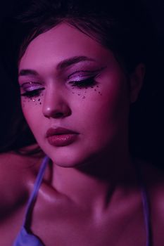 Artistic portrait of a woman with elegant pink makeup and rhinestones, exuding a moody ambiance.