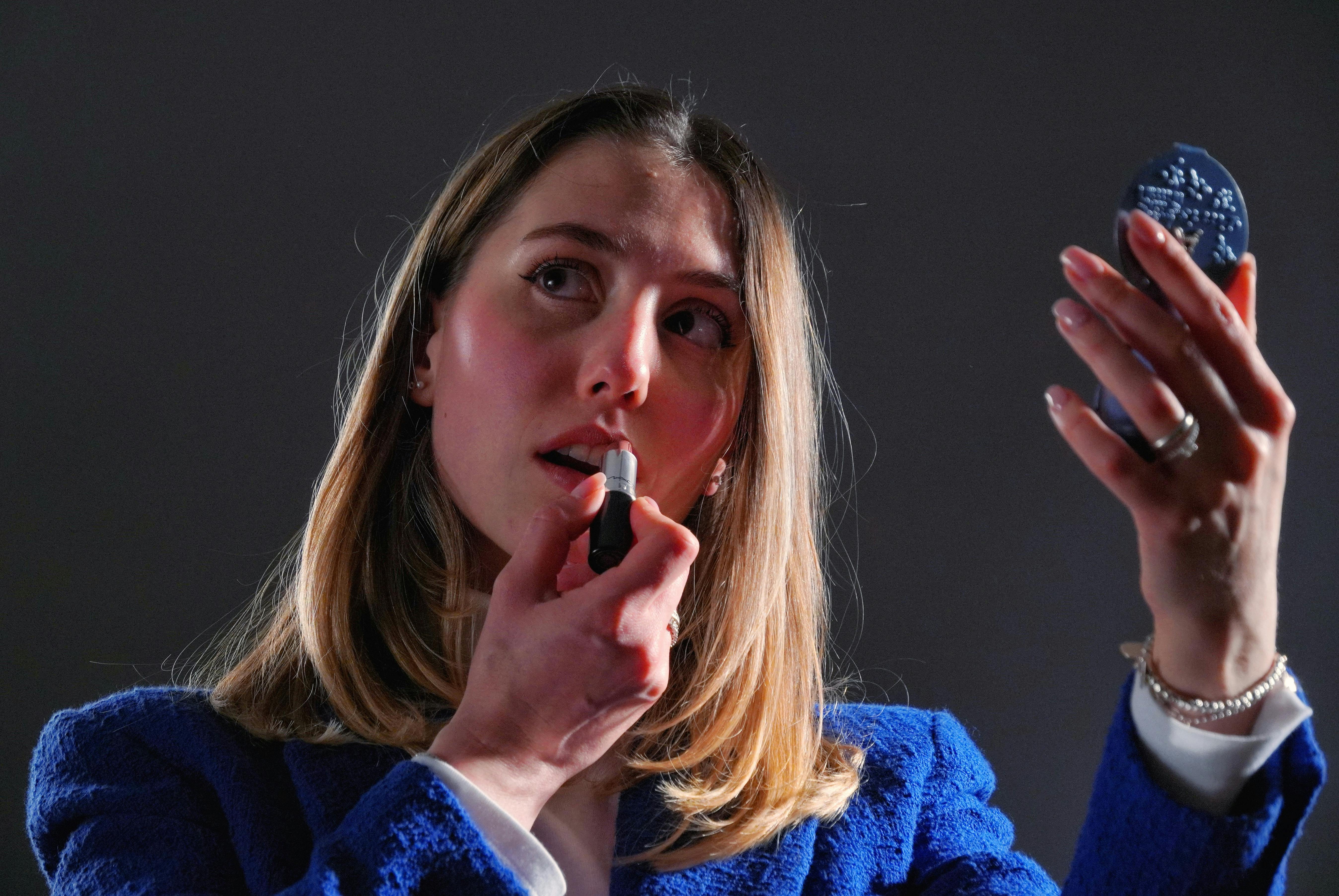 無料 思慮深いポーズでコンパクトミラーを使って口紅を塗っている若い成人女性。 写真素材