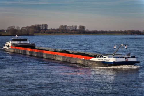 Free Large cargo ship navigating a calm inland waterway under clear skies. Stock Photo