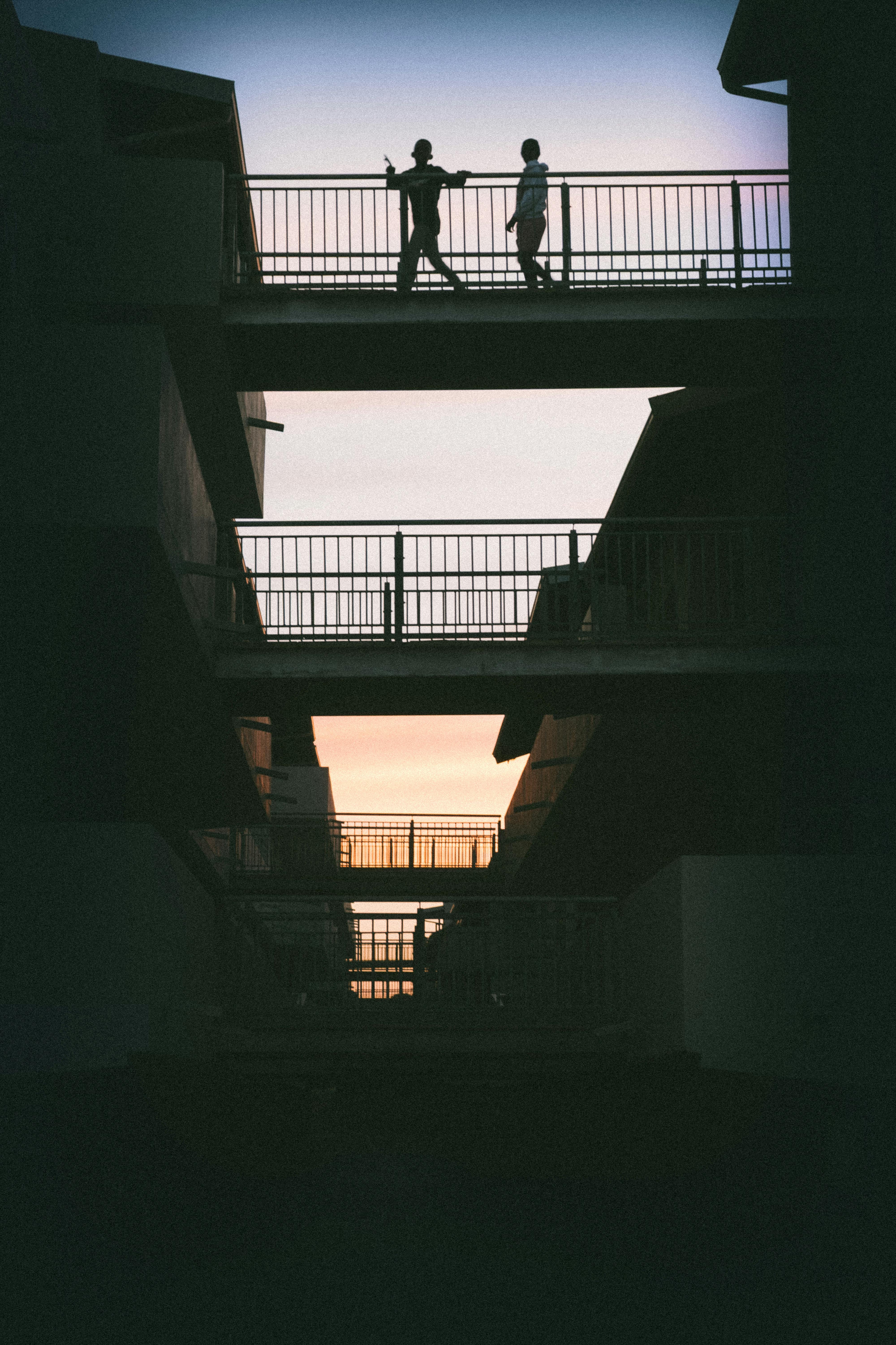 免费 日落时分，桥上孩子们的剪影构成了一幅引人注目的城市景象。 素材图片