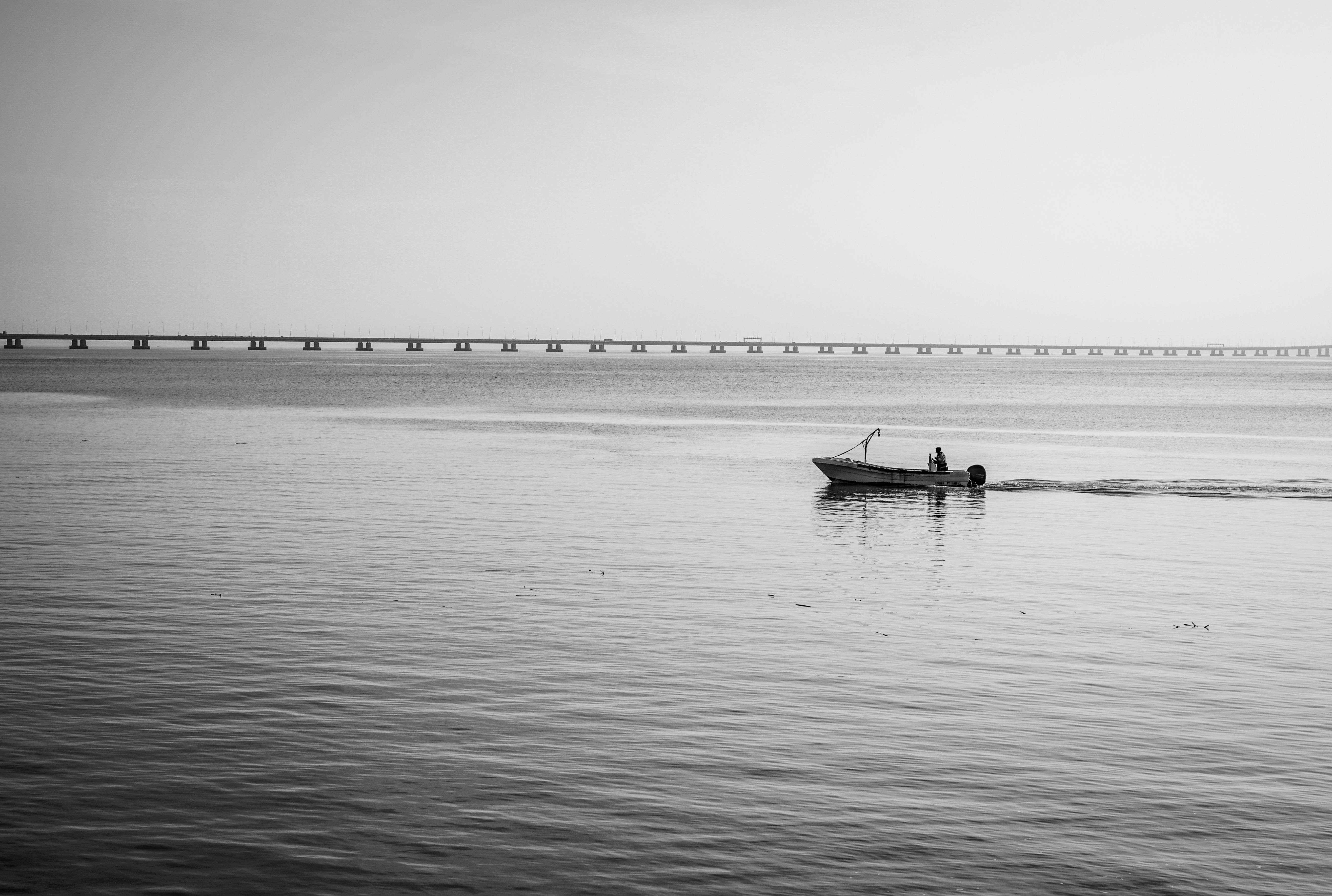 Black and White Boat Scene with Long Bridge · Free Stock Photo