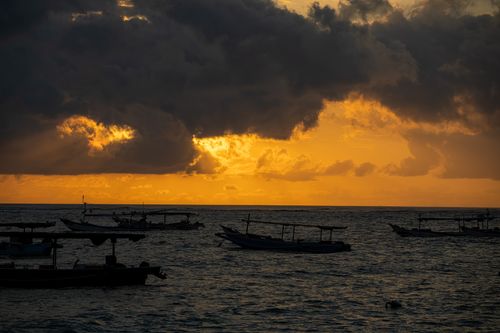 Free Majestic sunset with fishing boats silhouetted against vibrant clouds in Bali, Indonesia. Stock Photo
