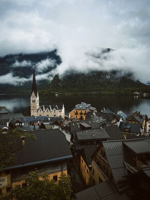 Free Picturesque view of Hallstatt village with foggy mountains and serene lake backdrop. Stock Photo