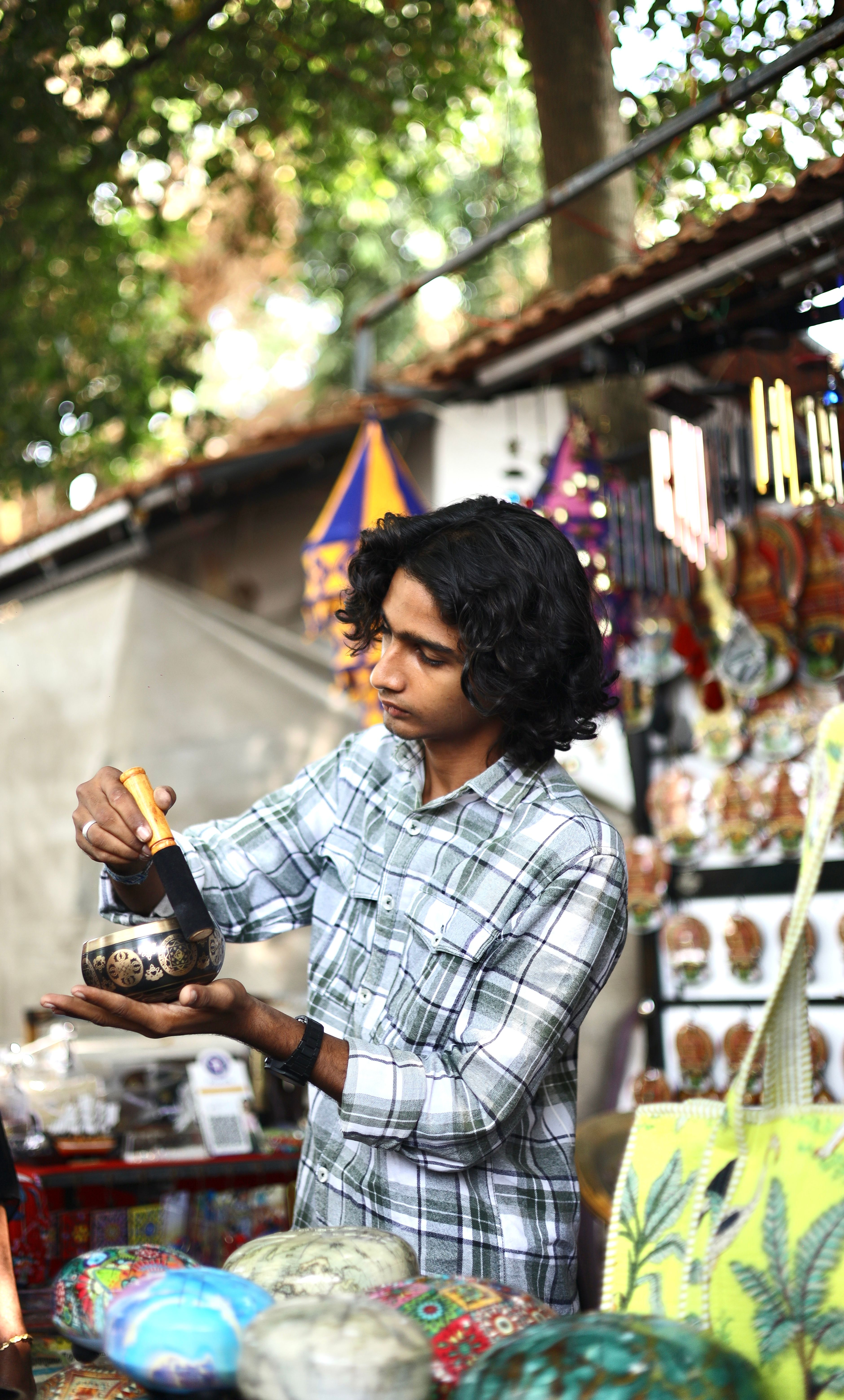 A young man explores a colorful market stall in India, sifting through unique handmade crafts.