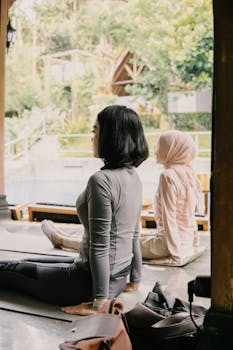 Two women practicing yoga outdoors in Jawa Barat, Indonesia, surrounded by nature.