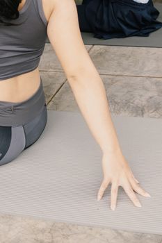 A woman in activewear practicing yoga on a mat outside in Jawa Barat, Indonesia.