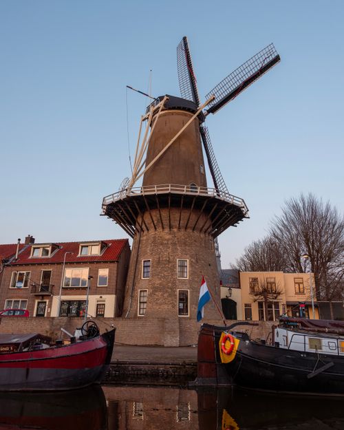 Free Charming windmill with houseboats in Gouda, Netherlands, during sunset with a clear sky. Stock Photo
