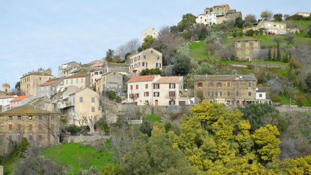Picturesque view of traditional houses on a hillside in Oletta, Corse, France, showcasing rustic architecture.