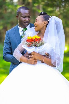 A joyful bride and groom celebrate their wedding outdoors with a beautiful bouquet.