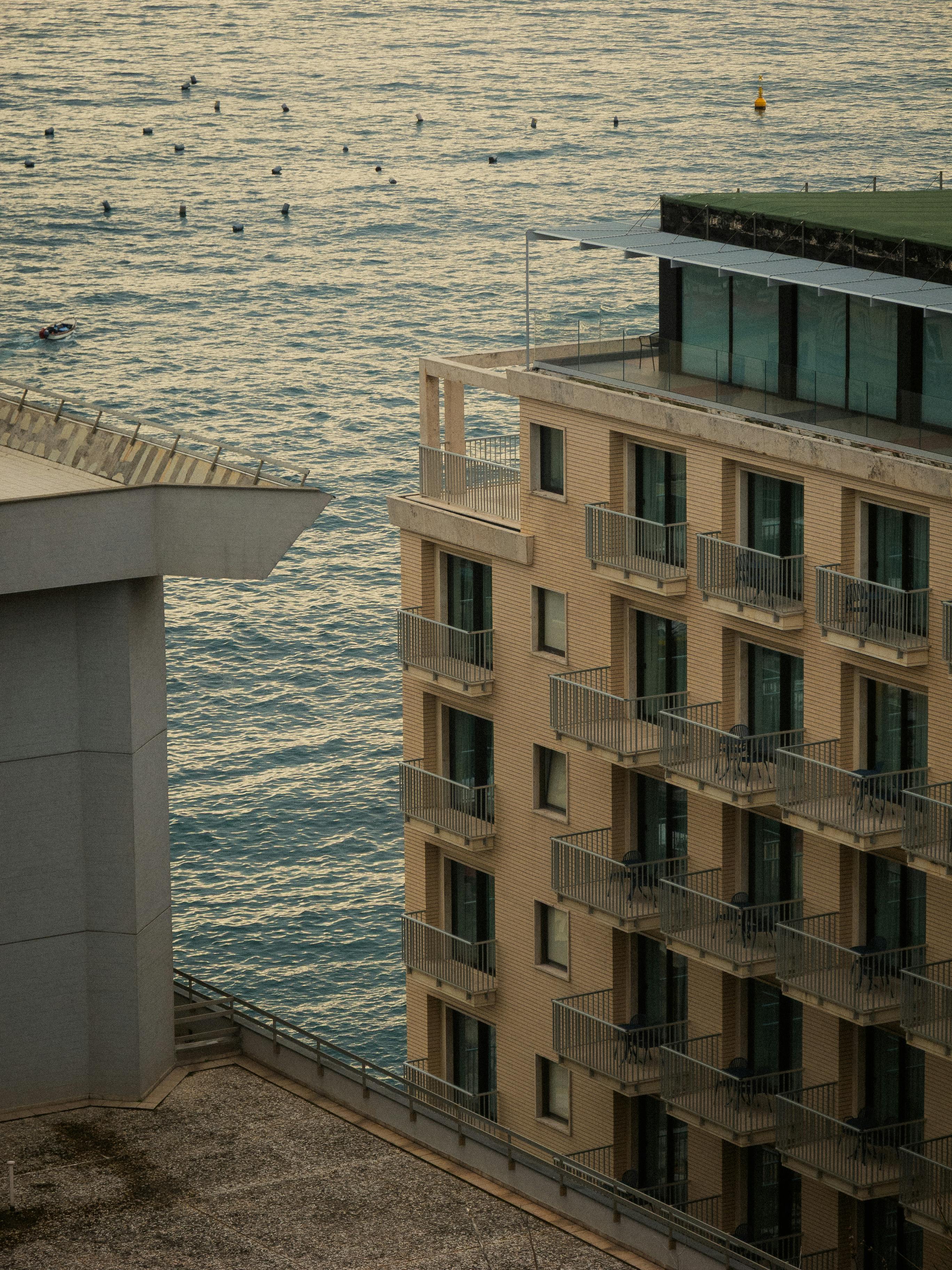 View of ocean and modern buildings at sunset, capturing tranquil urban life.