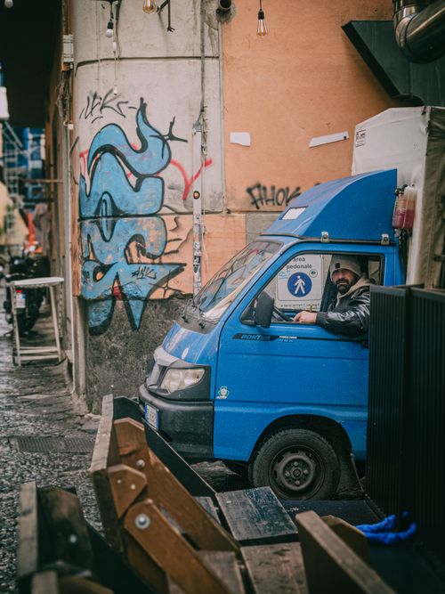 Free A vibrant street scene featuring a blue delivery van and graffiti art. Stock Photo