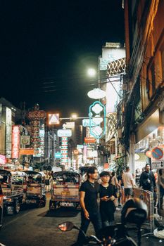 Experience the bustling nightlife of a Bangkok street market illuminated by neon signs and lively crowds.
