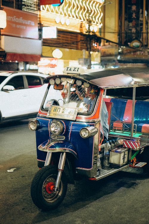 Free A colorful tuk-tuk taxi on a bustling street at night in Bangkok. Stock Photo