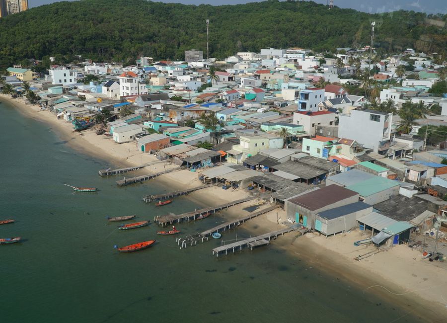 Discover the serene coastal village on Phu Quoc Island with vibrant houses and boats.