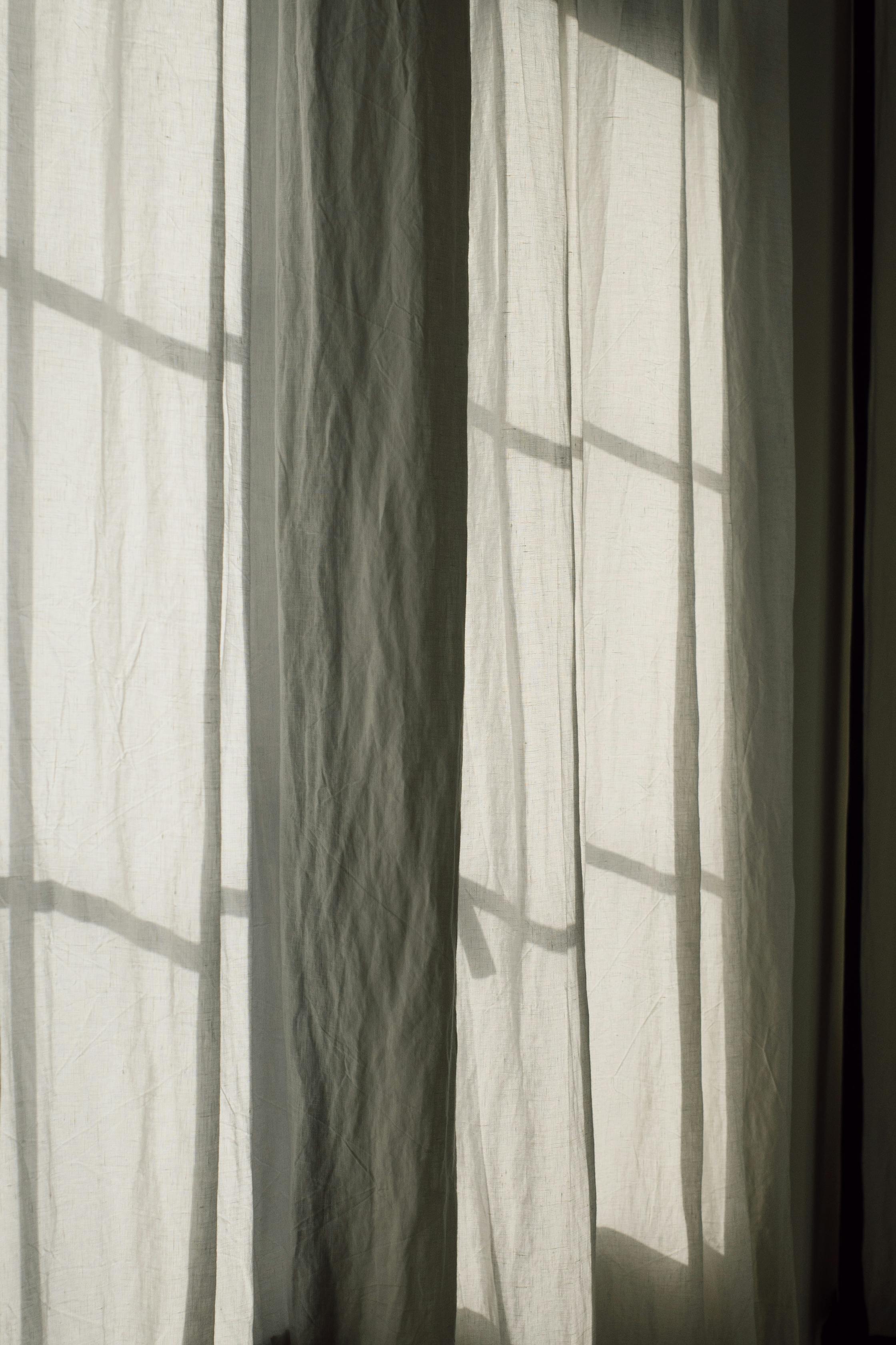 Free Soft sunlight filtering through elegant drapes creates a serene indoor ambiance. Stock Photo