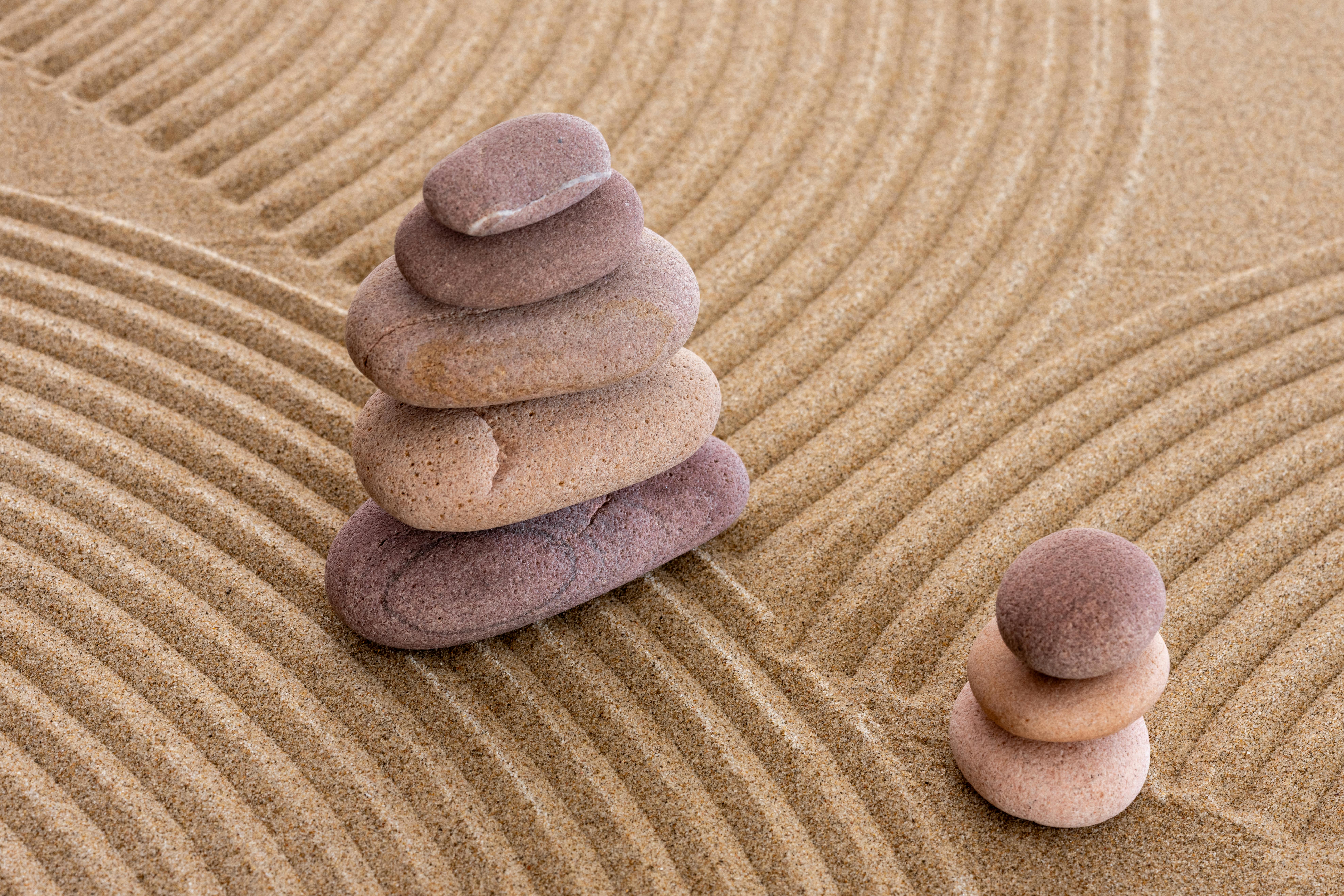 grátis Pedras zen serenas empilhadas sobre areia rastelada, simbolizando equilíbrio e tranquilidade. Foto profissional