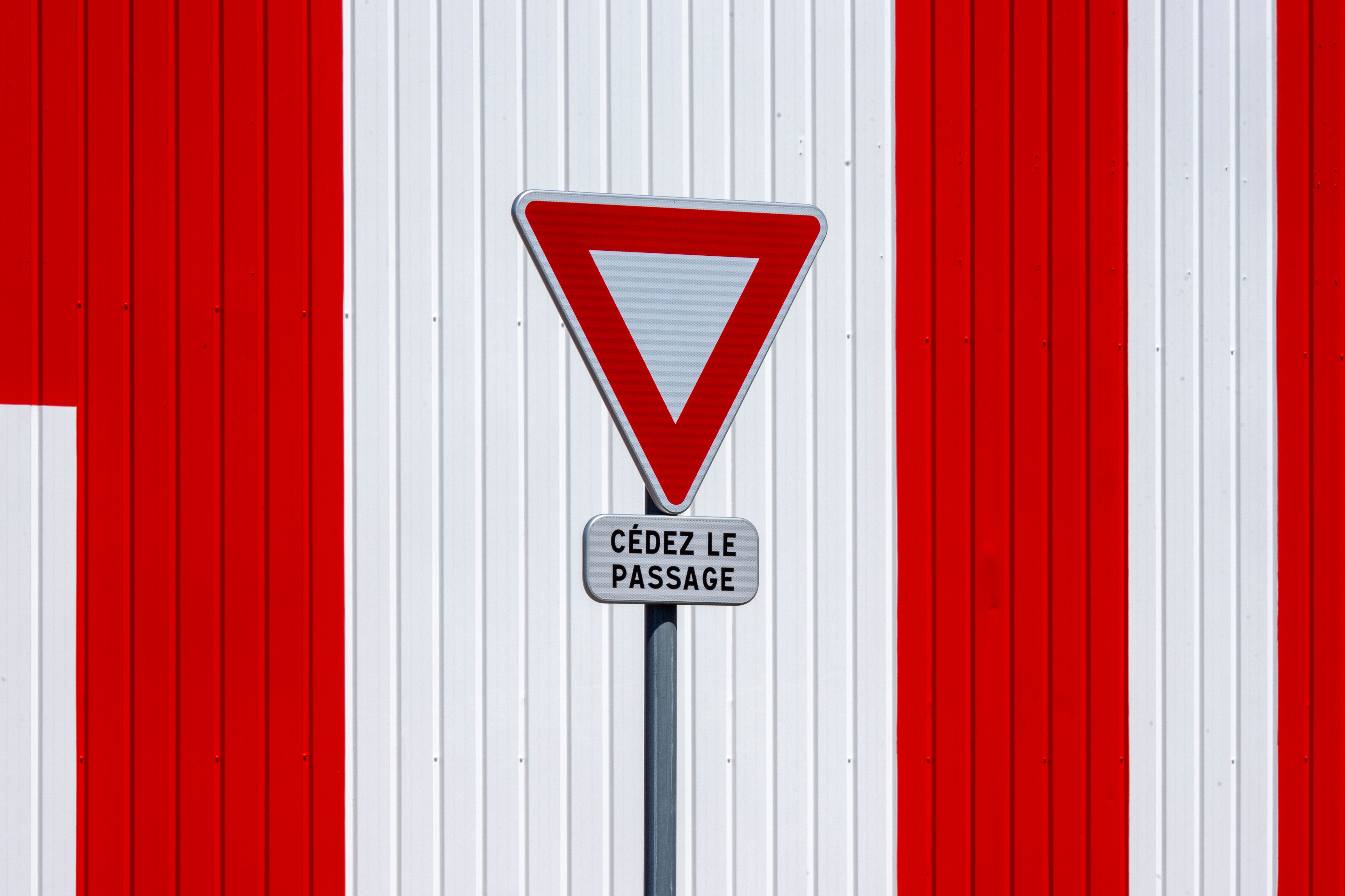 French Yield Sign on Striped Wall Background