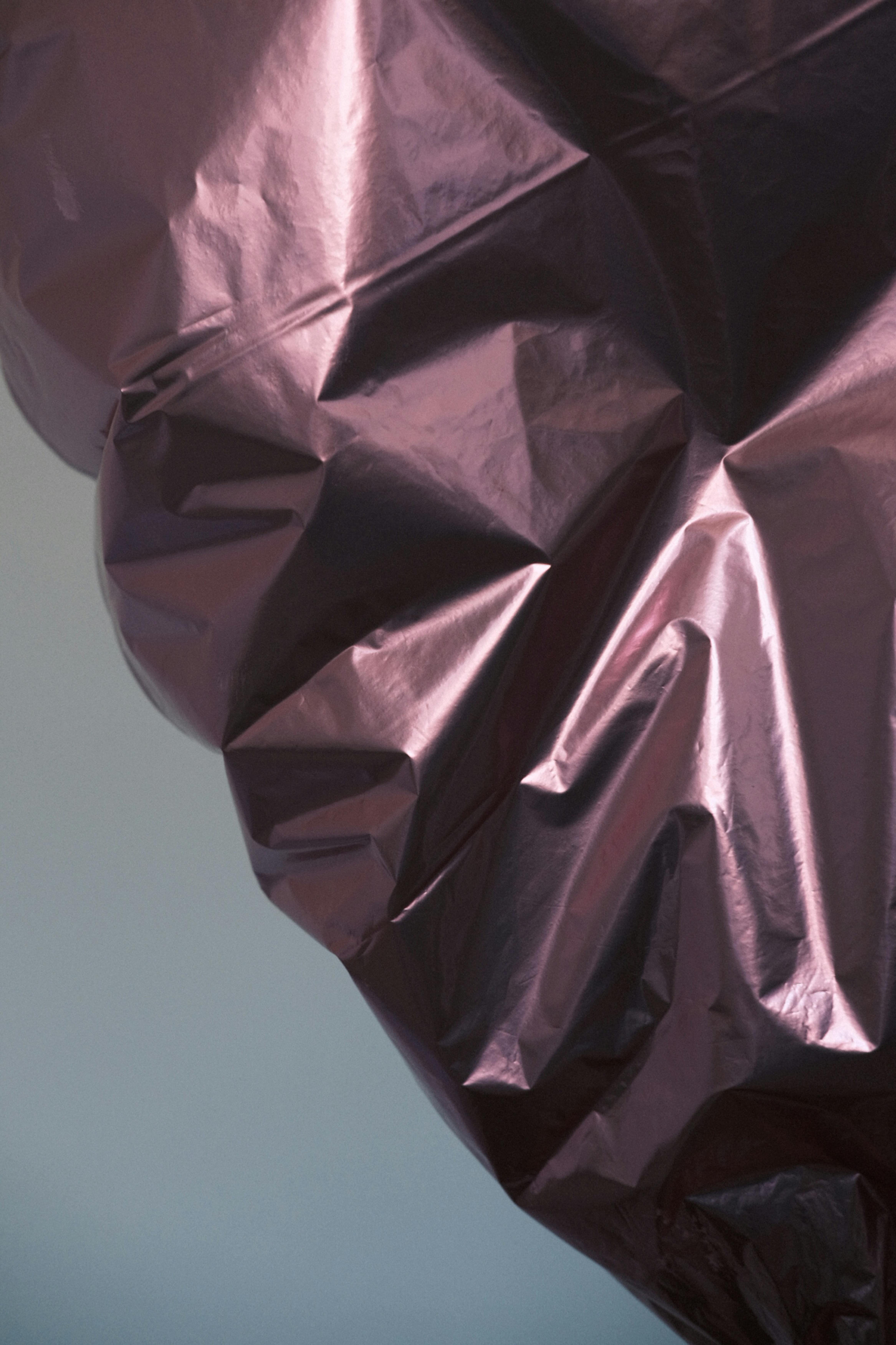 Kostnadsfria Närbild av skrynklig glänsande metallfolie med en subtil lila nyans, vilket skapar en abstrakt textur. Stock foto