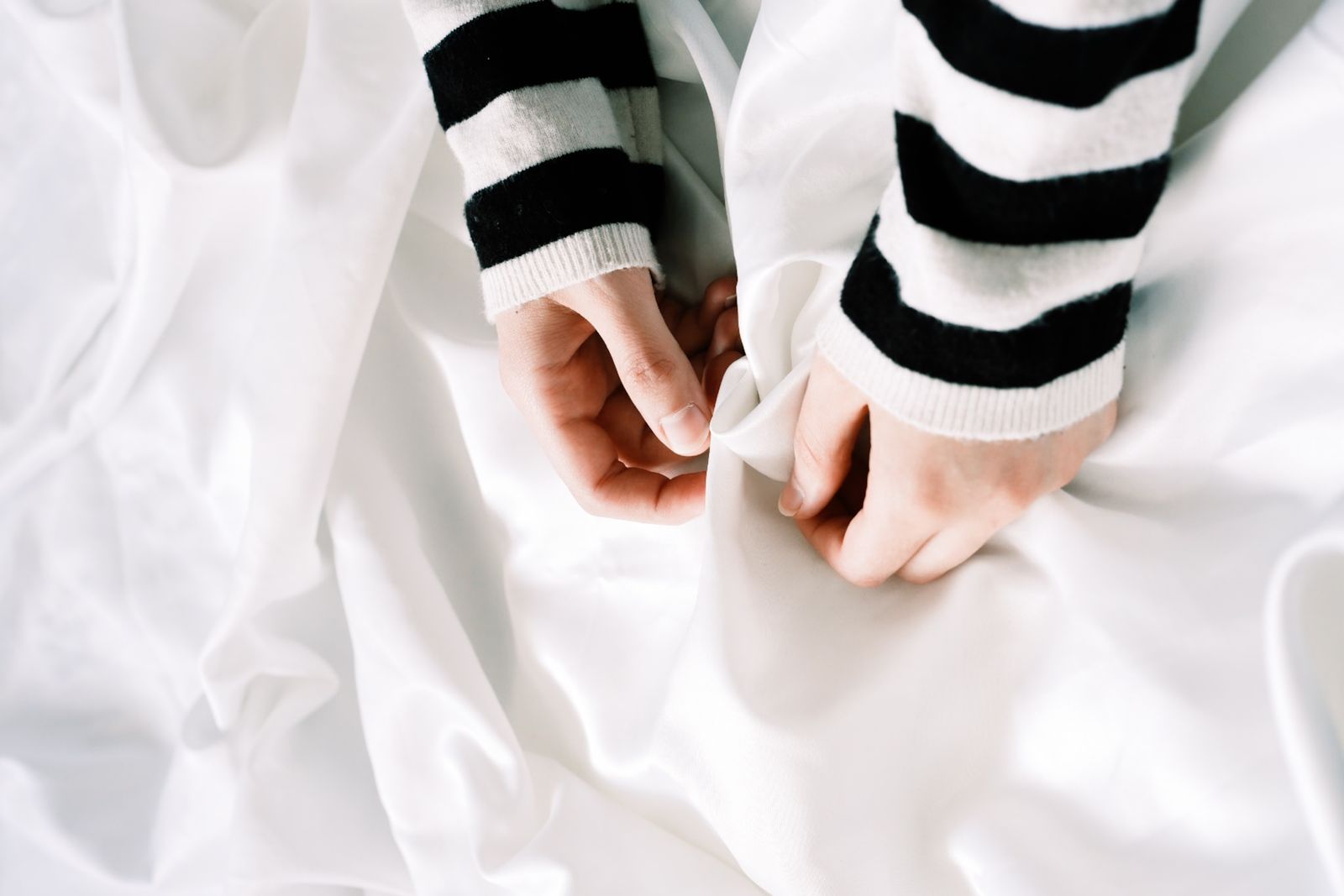Two hands gathering a length of white cloth — Beyzaa Yurtkuran on Pexels
