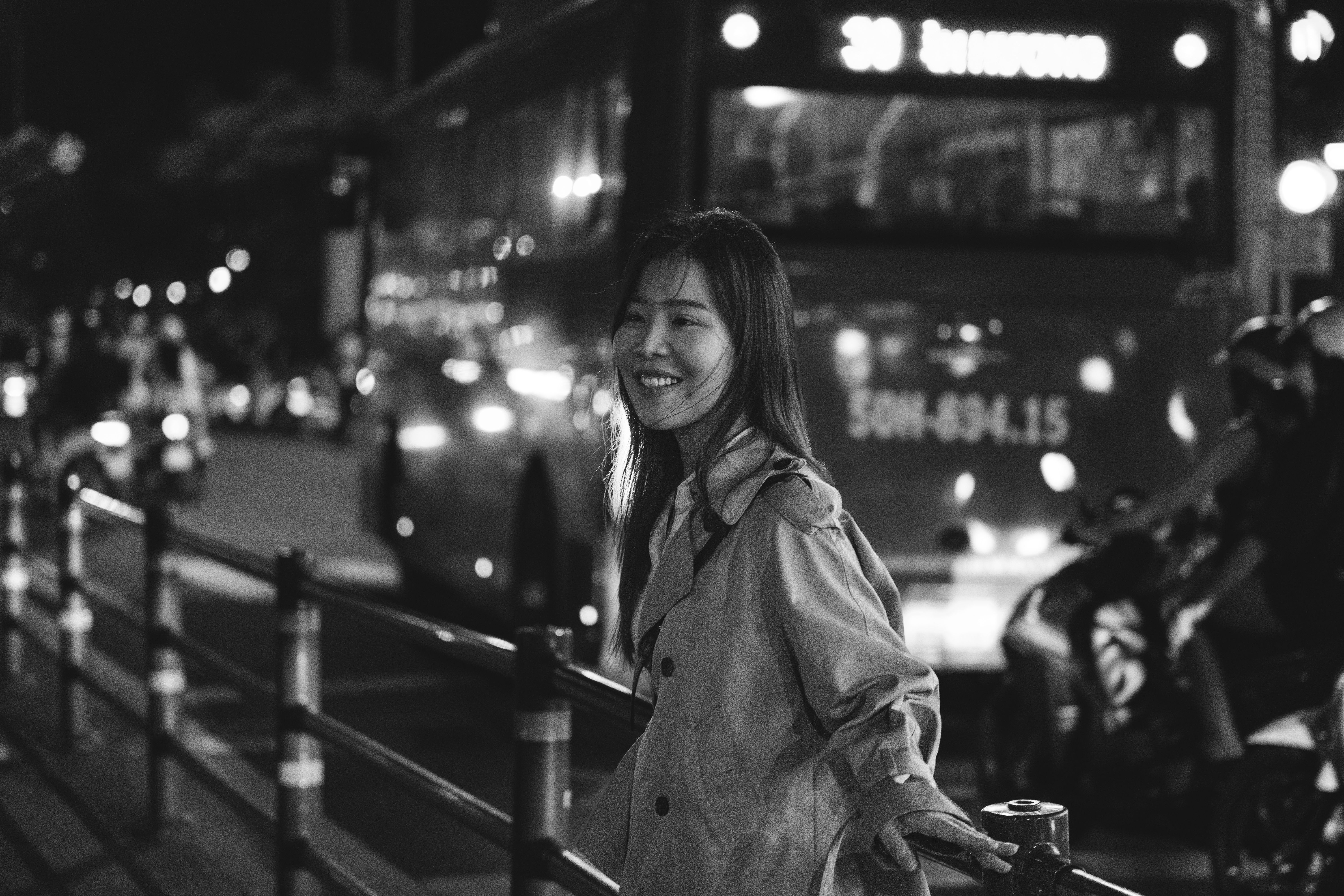 Uma mulher sorrindo em uma rua movimentada da cidade de Ho Chi Minh à noite, capturando a vibrante vida urbana.