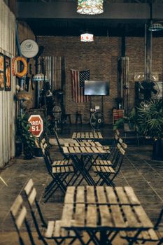 A warm, rustic industrial café setting in Bangkok featuring American décor and wooden furniture.