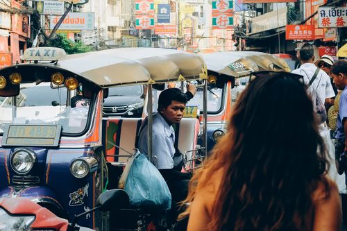 Free Vibrant street scene in Bangkok featuring a tuk-tuk and bustling crowd in colorful surroundings. Stock Photo
