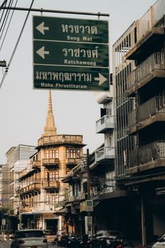 Captured street scene in Bangkok with directional signs and urban architecture.