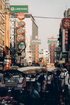 Vibrant street scene in Bangkok's Chinatown with tuk-tuks and colorful signs