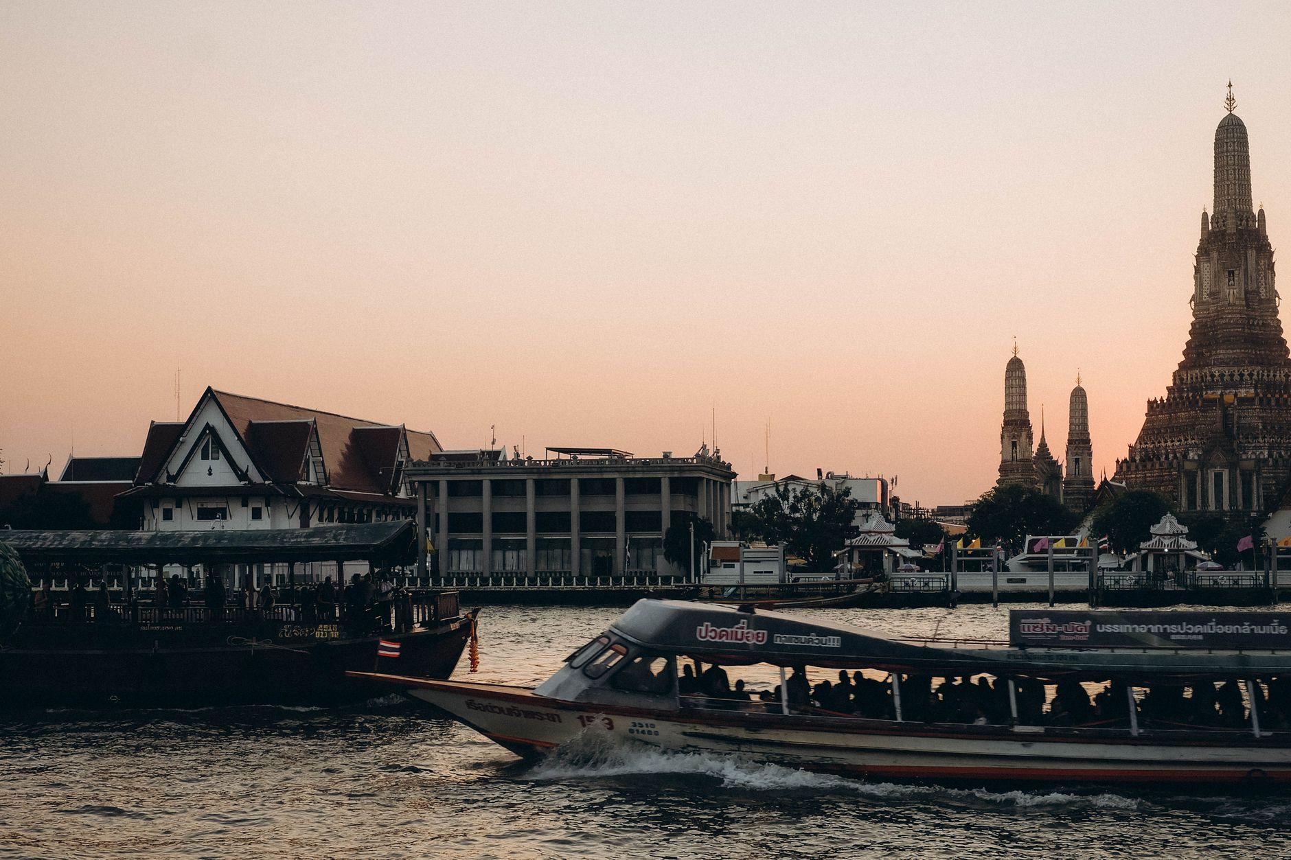 Traditional teak longtail boat cruising past Wat Arun on the Chao Phraya