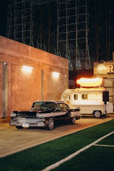 Classic vintage car parked near a retro food trailer, illuminated at night in Bangkok.