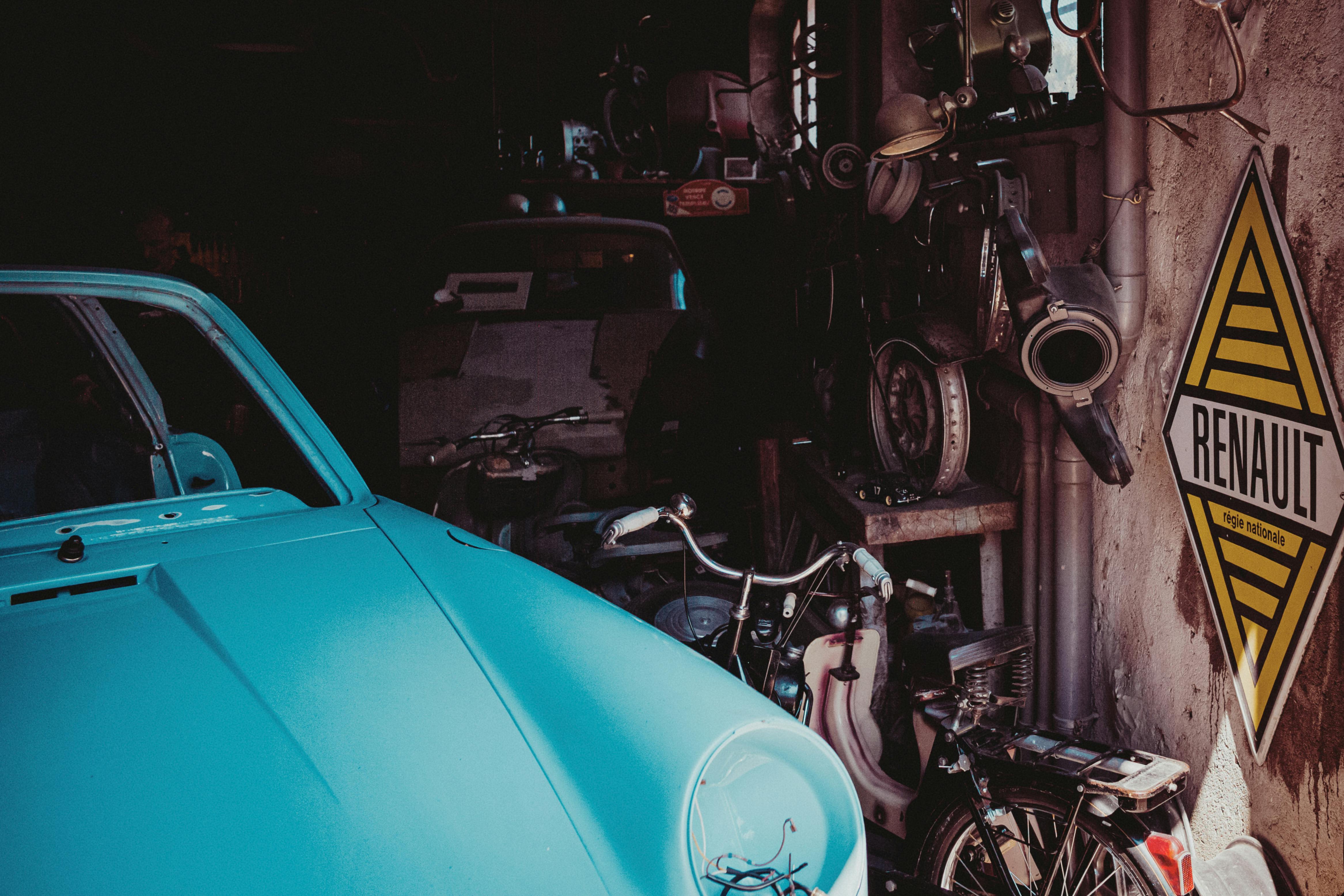 grátis Garagem vintage com placa da Renault e veículos antigos que evocam a nostalgia automotiva. Foto profissional