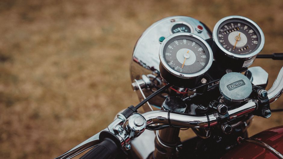 A detailed view of a vintage motorcycle's dashboard featuring classic gauges and chrome details.