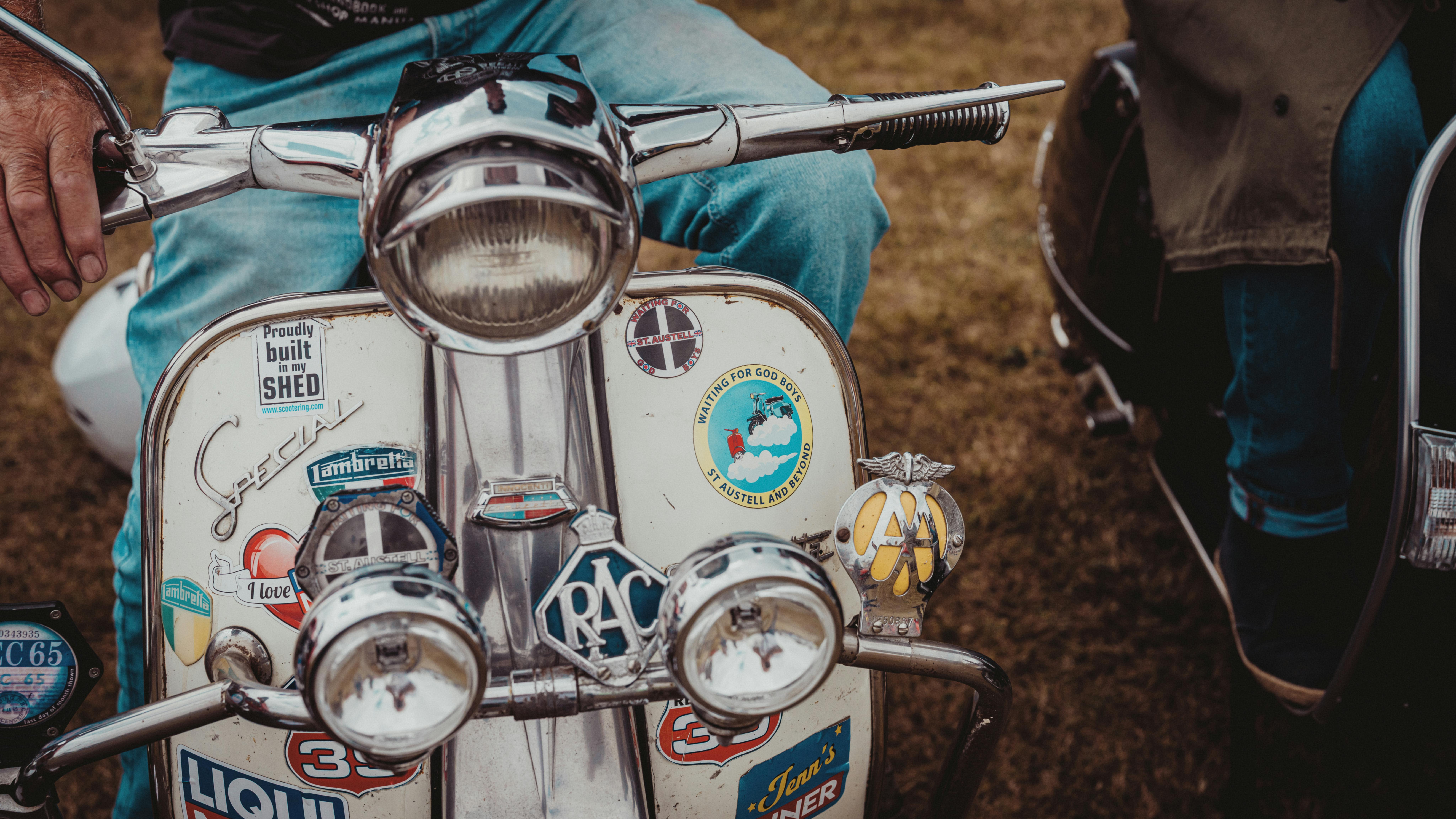 Gratuit Gros plan sur un scooter vintage orné de divers autocollants et emblèmes, illustrant un style automobile nostalgique. Photos