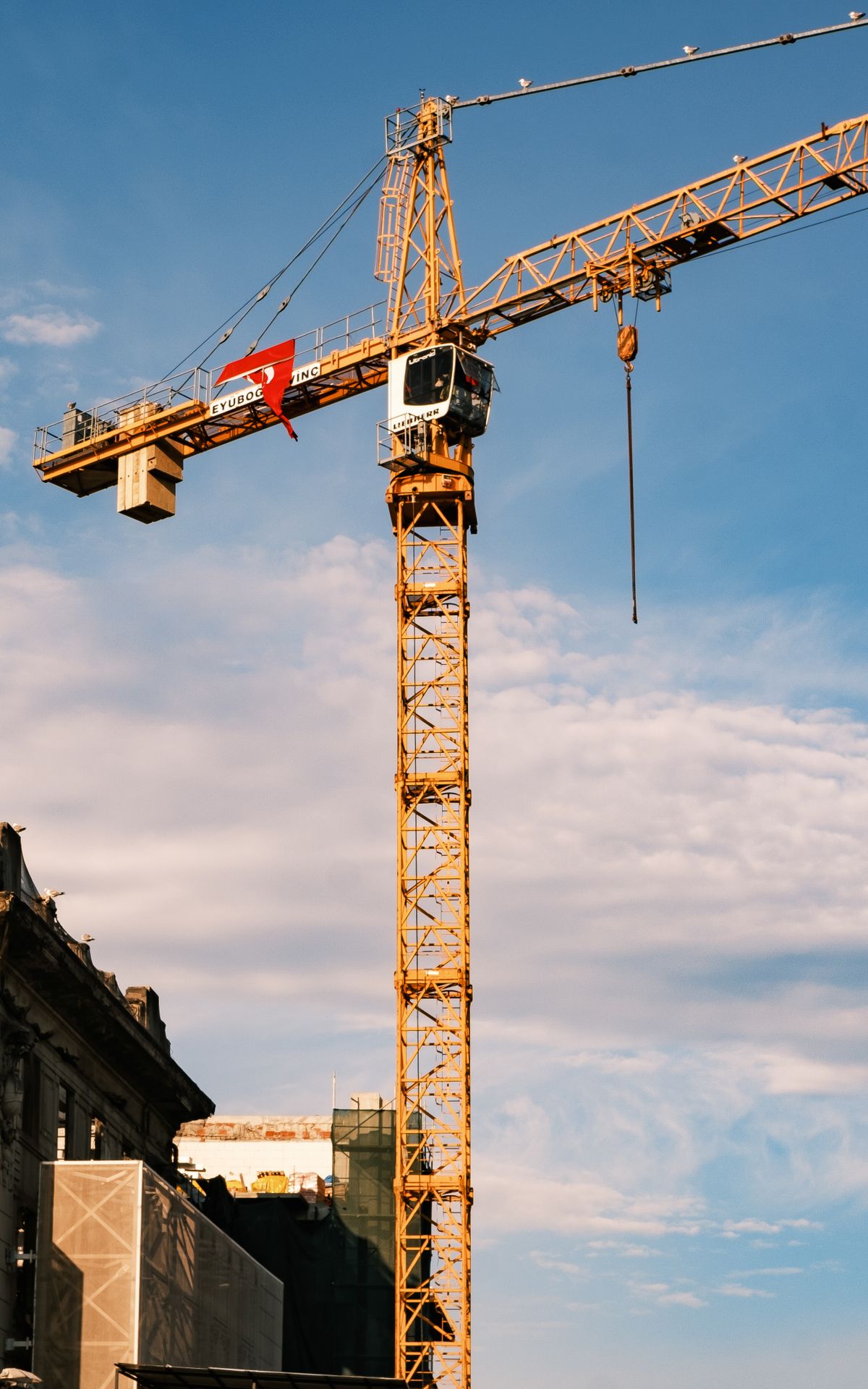 Grue à tour jaune dressée sur fond de ciel bleu, symbole du génie civil en action