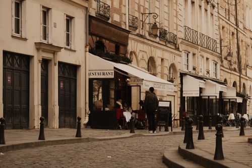 Free Cobblestone street in Paris with cafes and classic architecture, evoking a vintage urban mood. Stock Photo